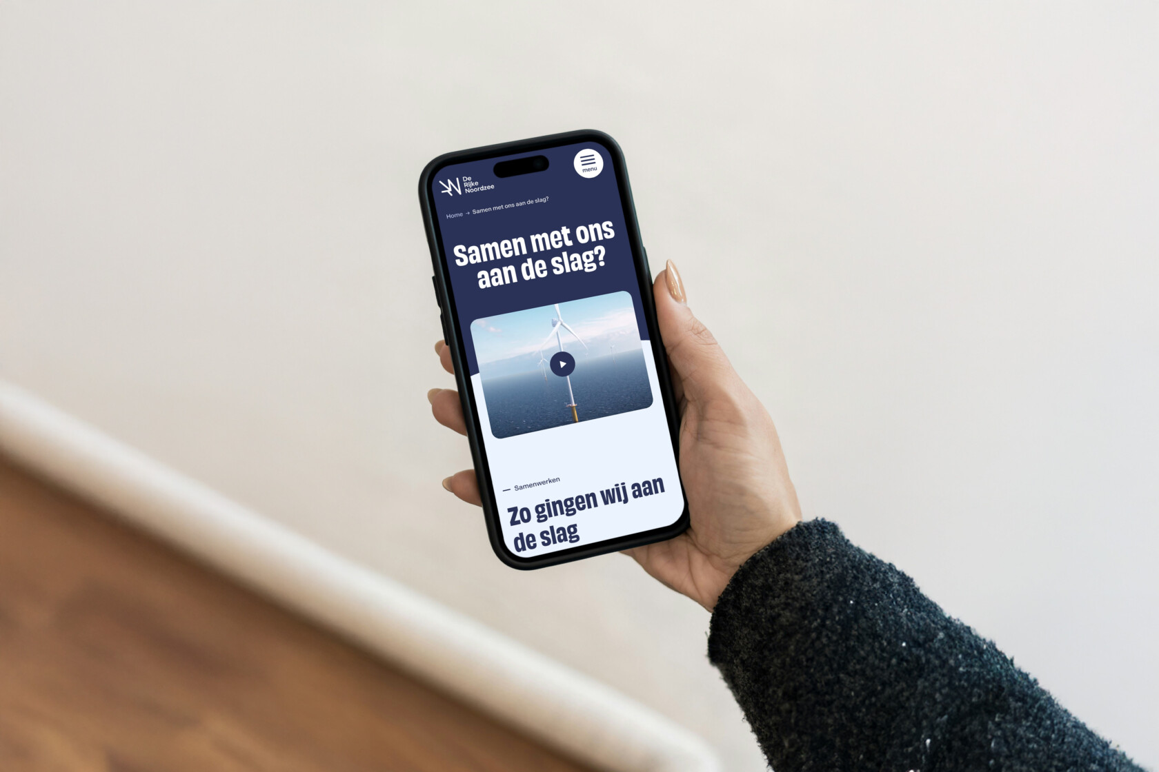 Mobiel in hand met De Rijke Noordzee website op scherm